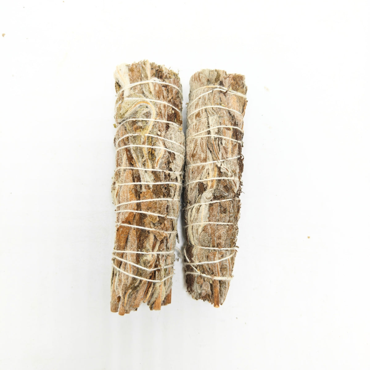 Two natural white sage smudge sticks tied with cotton string on white background