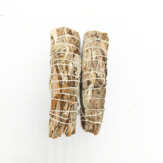 Two natural white sage smudge sticks tied with cotton string on white background